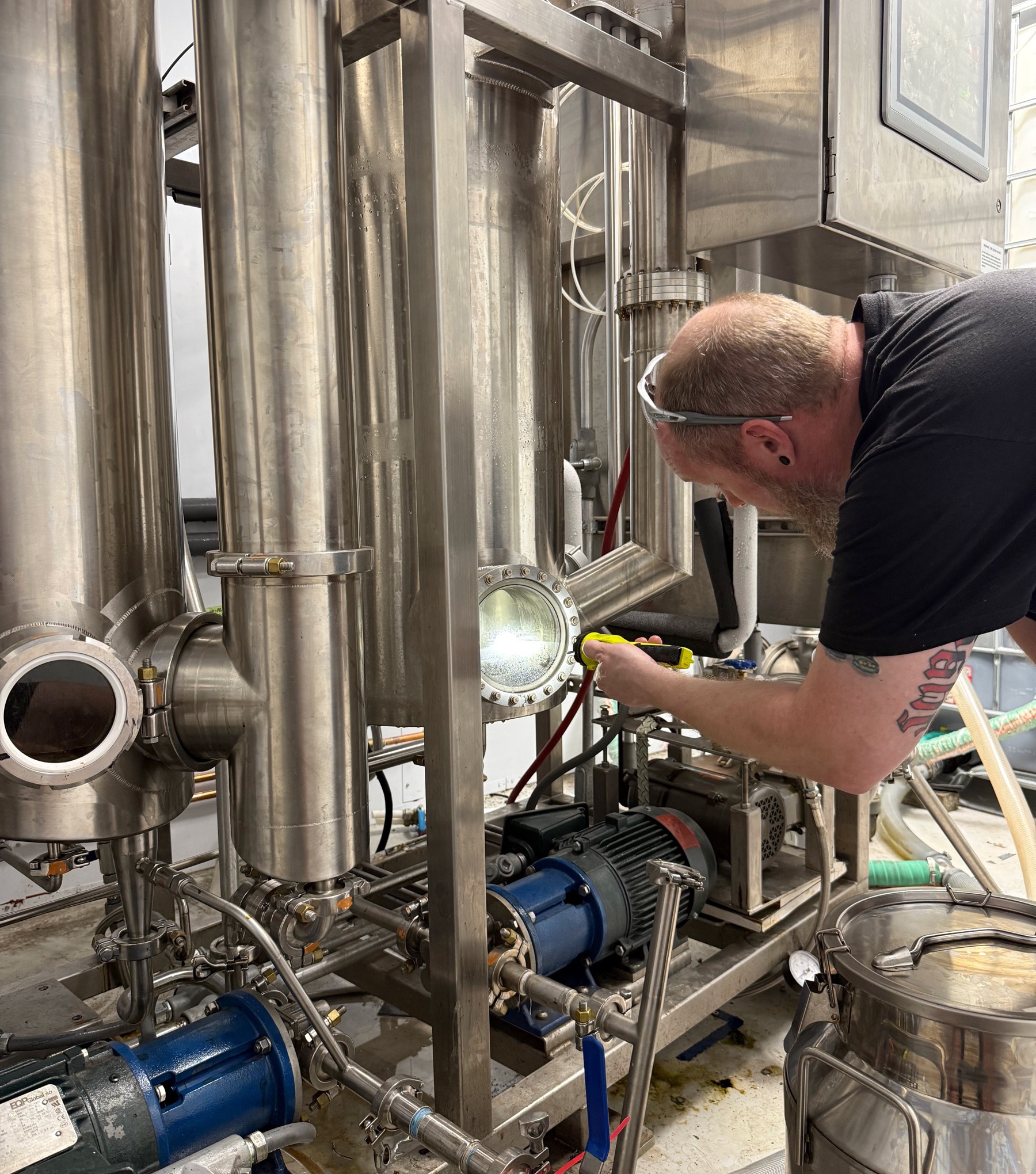 Operator working on stainless extraction equipment in a cannabis facility